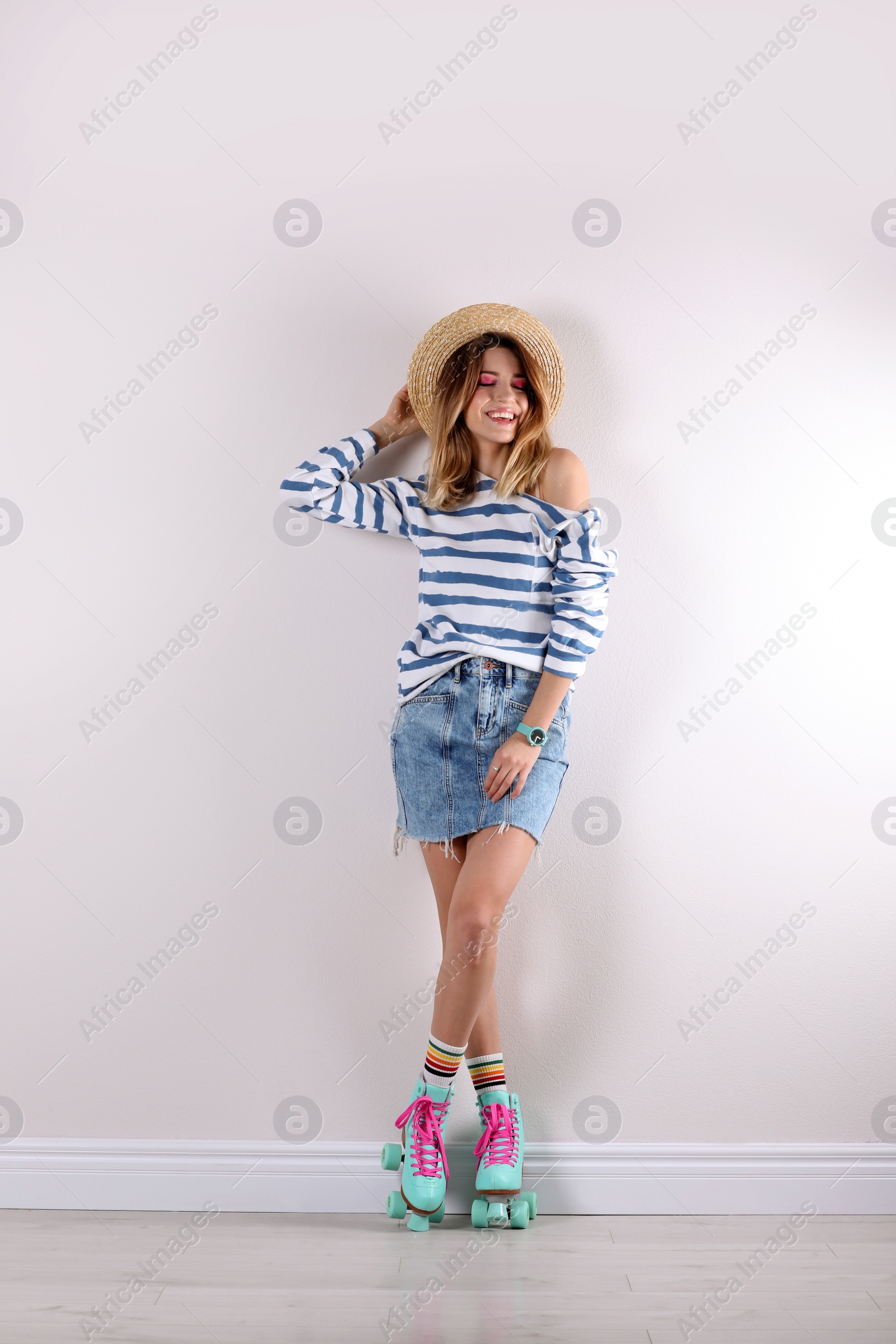 Photo of Young woman with retro roller skates near white wall