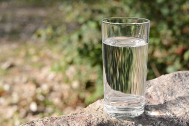 Photo of Glass of water on stone outdoors, space for text