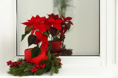 Photo of Potted poinsettia and festive decor on windowsill in room, space for text. Christmas traditional flower