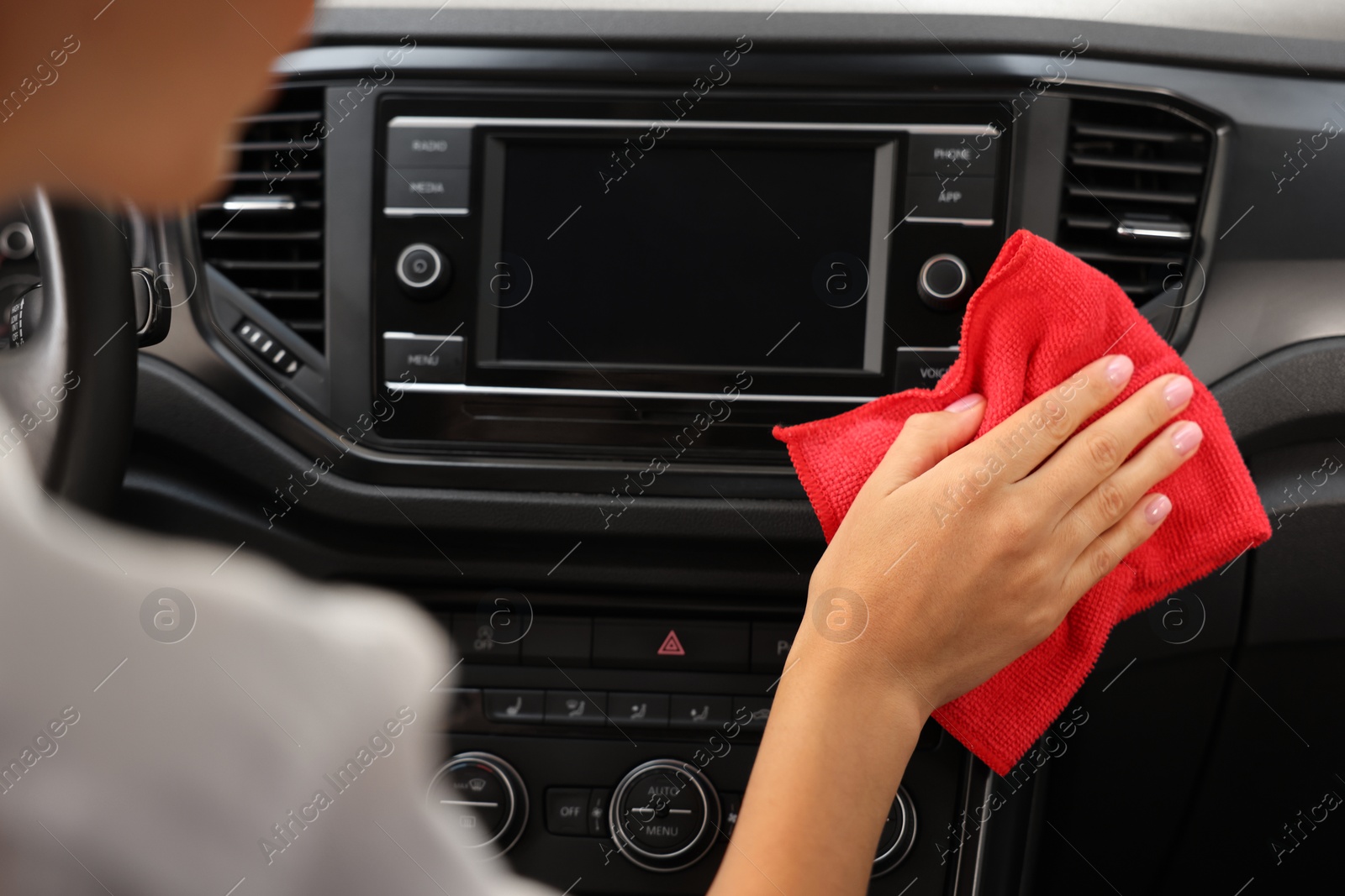 Photo of Woman cleaning center console with rag in car, closeup