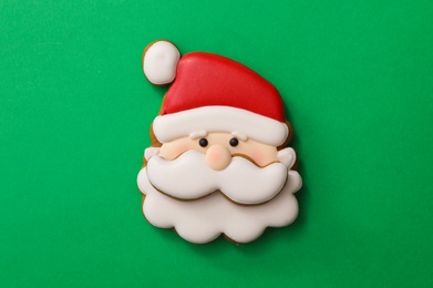 Photo of Christmas Santa Claus face shaped gingerbread cookie on green background, top view