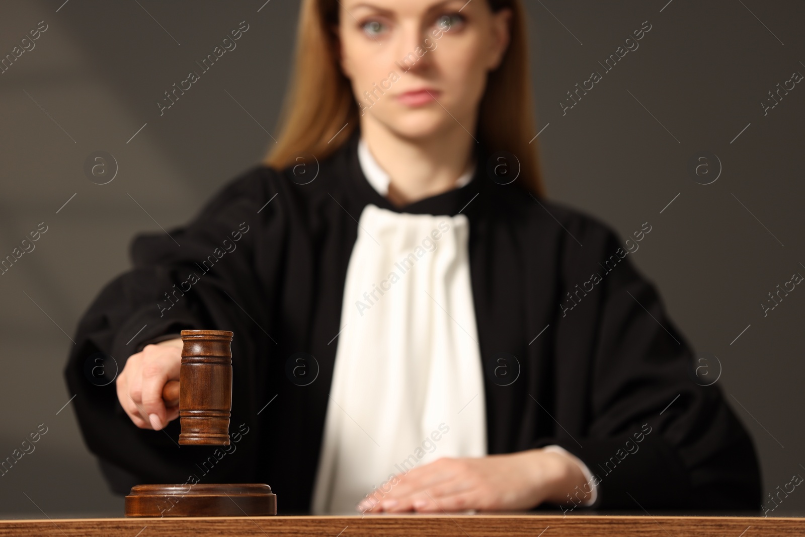 Photo of Judge striking mallet at wooden table in courtroom, selective focus