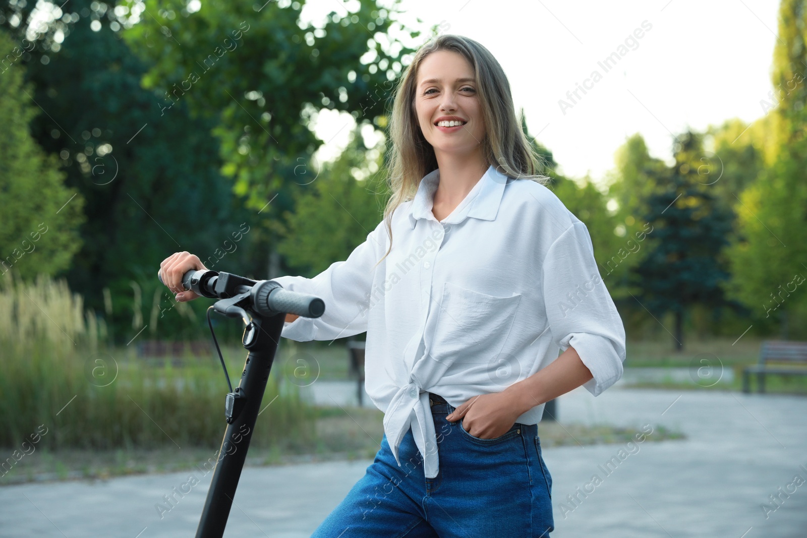 Photo of Happy woman with modern electric kick scooter in park