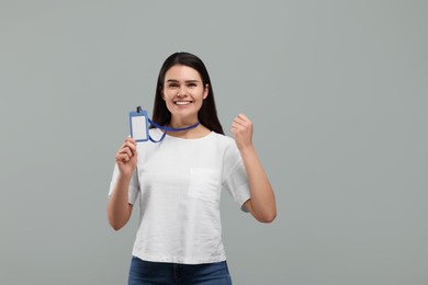 Emotional woman holding vip pass badge on grey background. Space for text