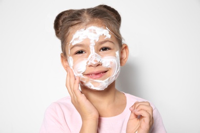 Photo of Cute little girl with soap foam on face against white background