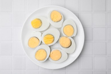 Photo of Fresh hard boiled eggs on white tiled table, top view