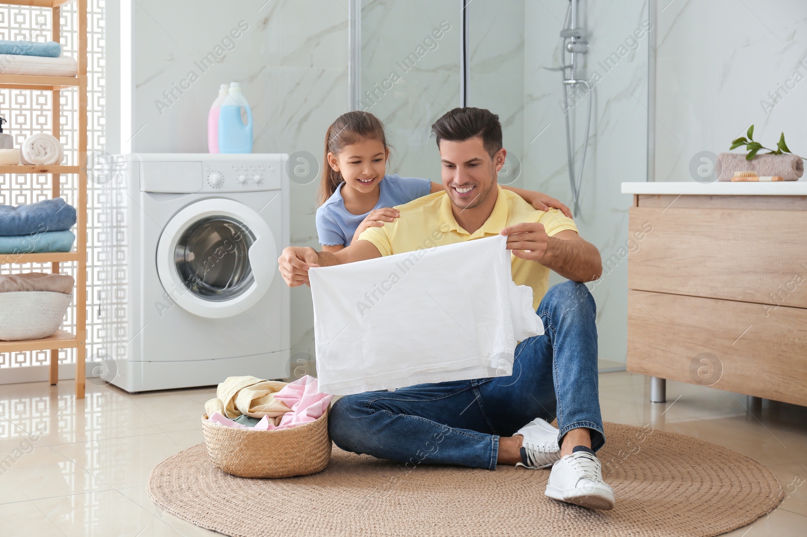 Photo of Father and little daughter with clean laundry in bathroom