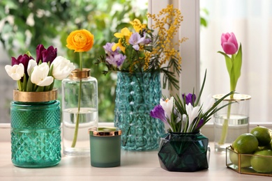 Photo of Different beautiful spring flowers and candle on window sill