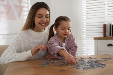 Photo of Woman and his little daughter playing with puzzles at home