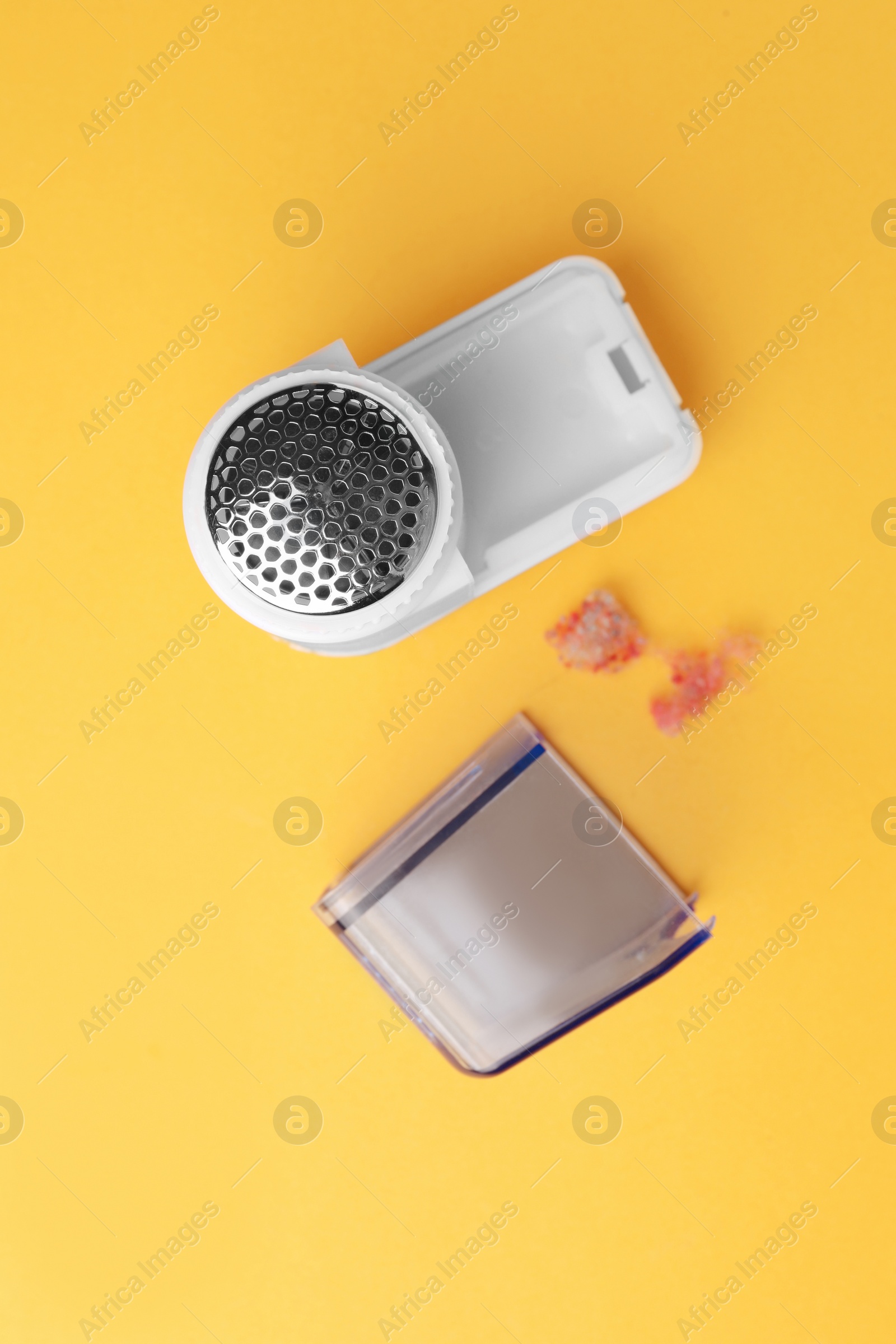 Photo of Modern fabric shaver with fuzz on yellow background, flat lay