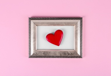 Photo of Vintage photo frame with decorative red heart on color background, top view