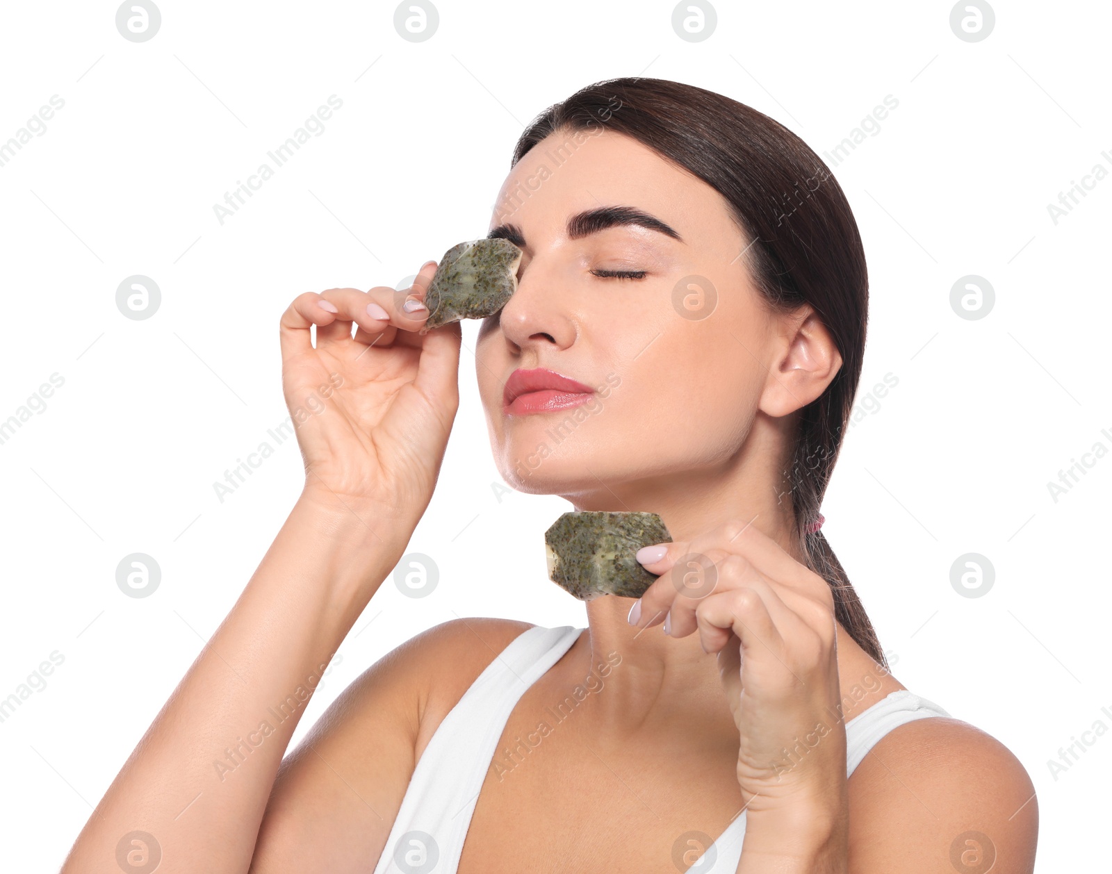 Photo of Beautiful woman applying green tea bags on skin under eyes against white background