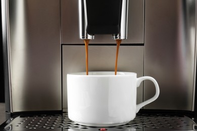 Photo of Modern espresso machine pouring coffee into cup, closeup