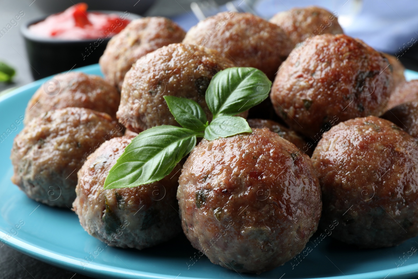 Photo of Tasty cooked meatballs and basil on plate, closeup view