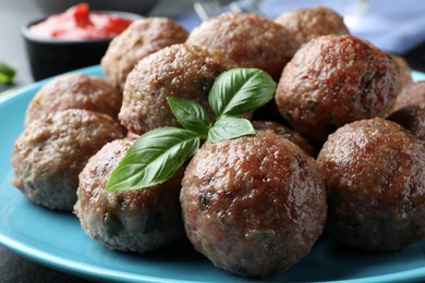 Photo of Tasty cooked meatballs and basil on plate, closeup view