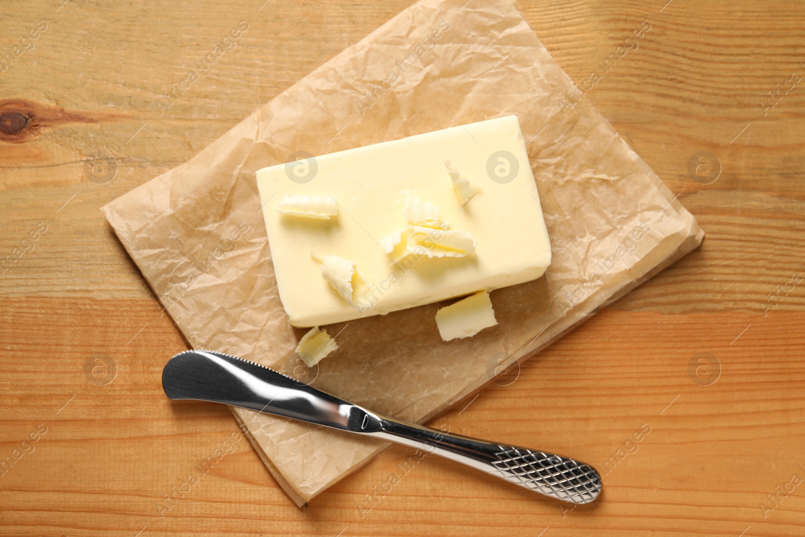 Photo of Tasty butter and knife on wooden table, top view