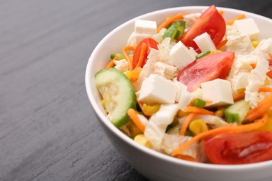 Tasty salad with Chinese cabbage, carrot, cheese, cucumber, corn and tomato on black table, closeup. Space for text