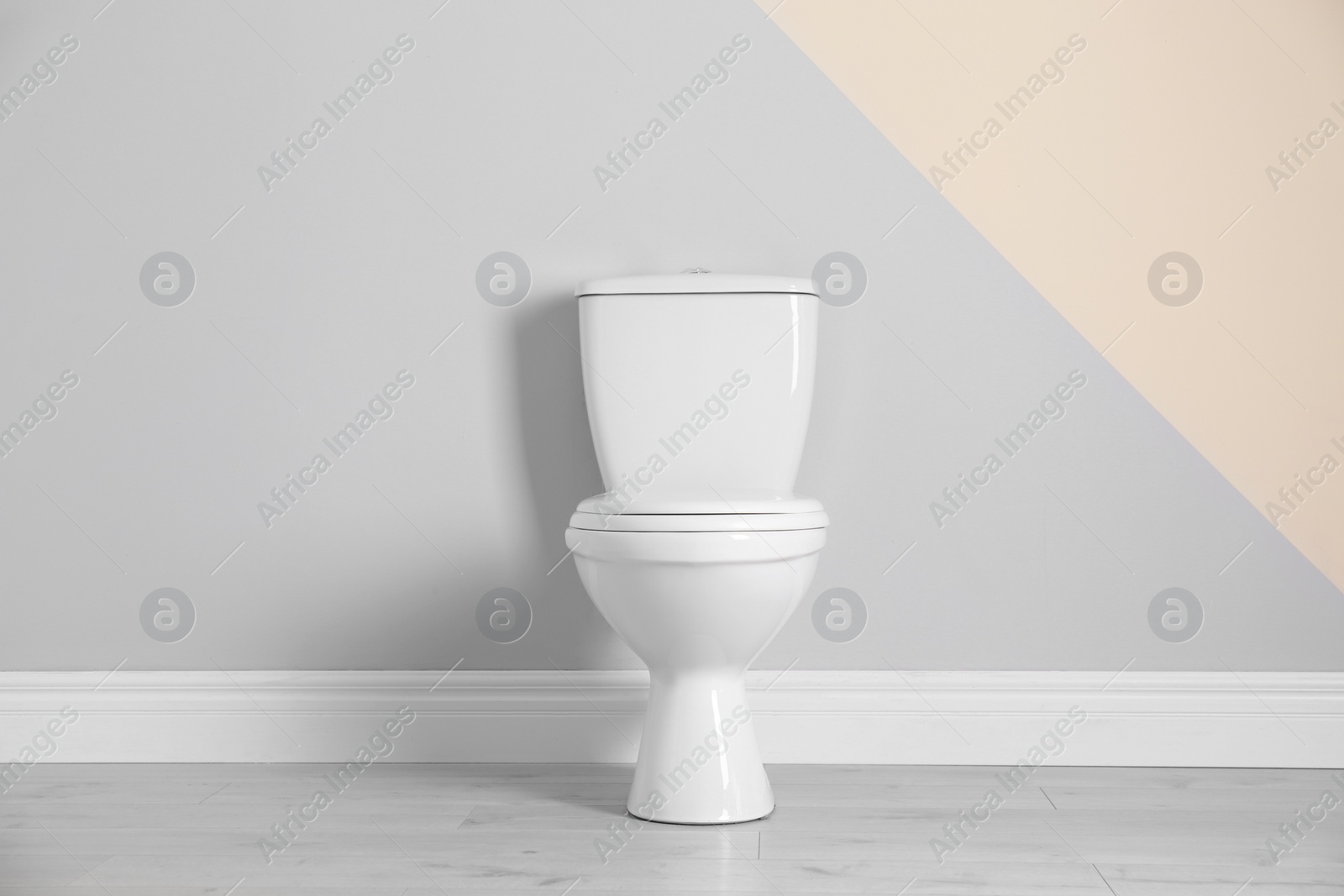 Photo of New toilet bowl near color wall indoors