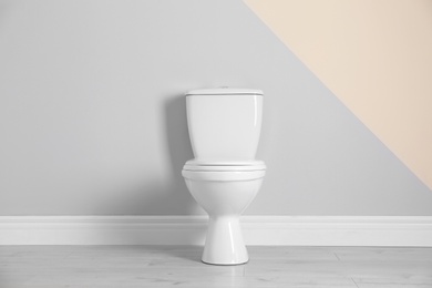 New toilet bowl near color wall indoors