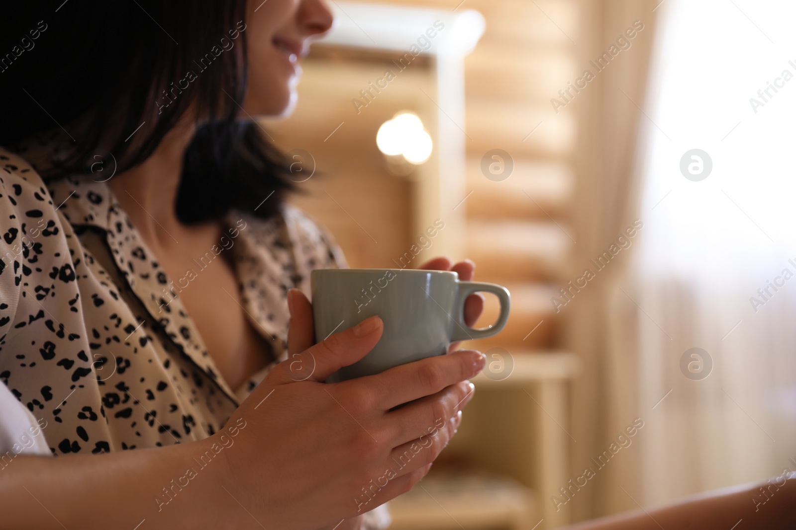 Photo of Young woman in pajamas with drink at home, closeup. Lazy morning