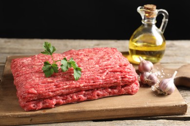 Photo of Raw ground meat, garlic, oil and parsley on wooden table