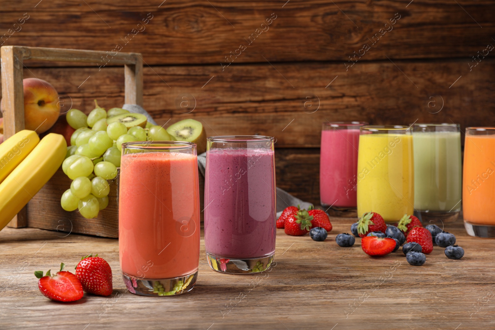 Photo of Glasses with different tasty smoothies and ingredients on wooden table