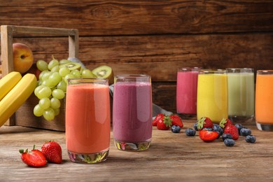 Photo of Glasses with different tasty smoothies and ingredients on wooden table