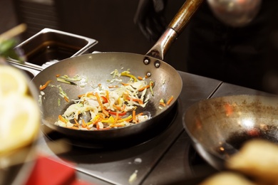 Photo of Man frying delicious vegetables in kitchen, closeup