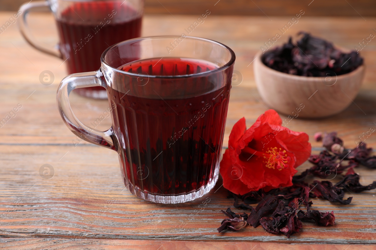 Photo of Delicious hibiscus tea and dry flowers on wooden table