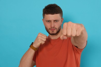 Photo of Young man ready to fight on light blue background