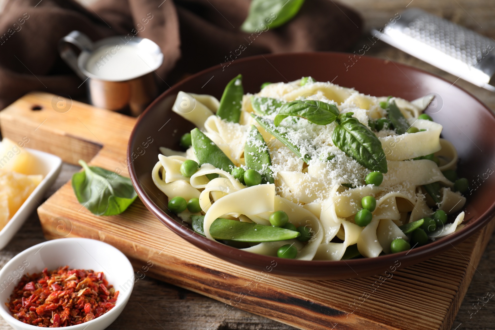 Photo of Delicious pasta with green peas, fresh basil and cheese on wooden table, closeup