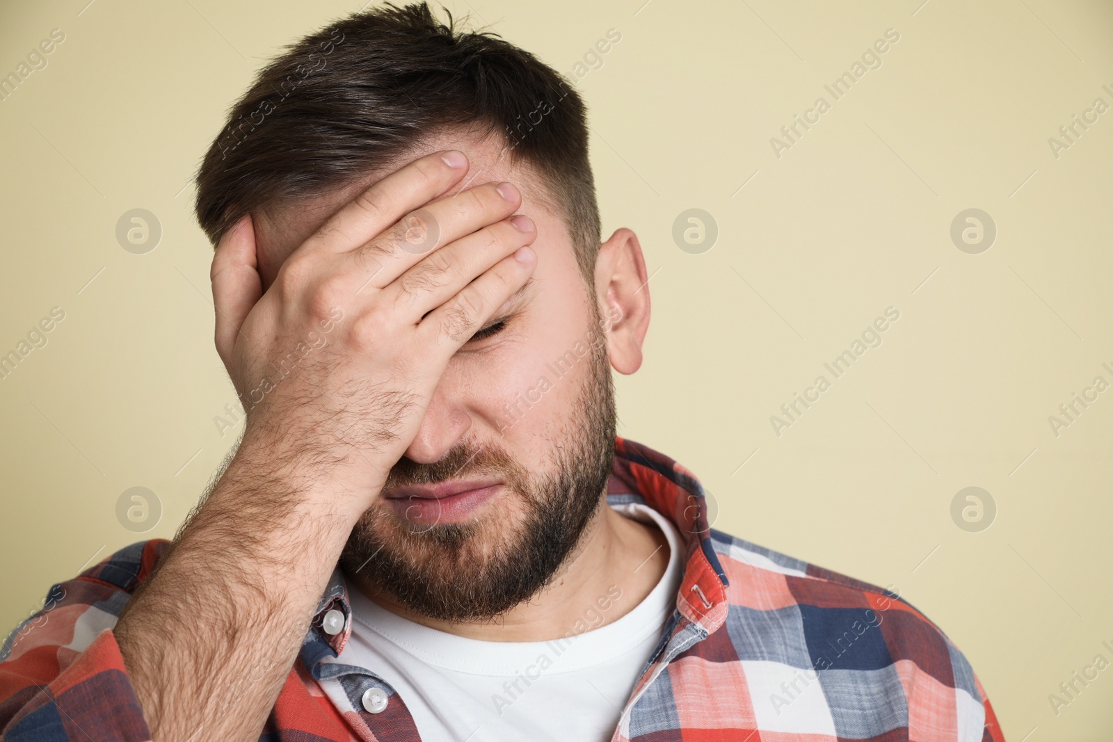 Photo of Man suffering from migraine on light green background, closeup