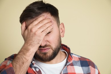 Photo of Man suffering from migraine on light green background, closeup