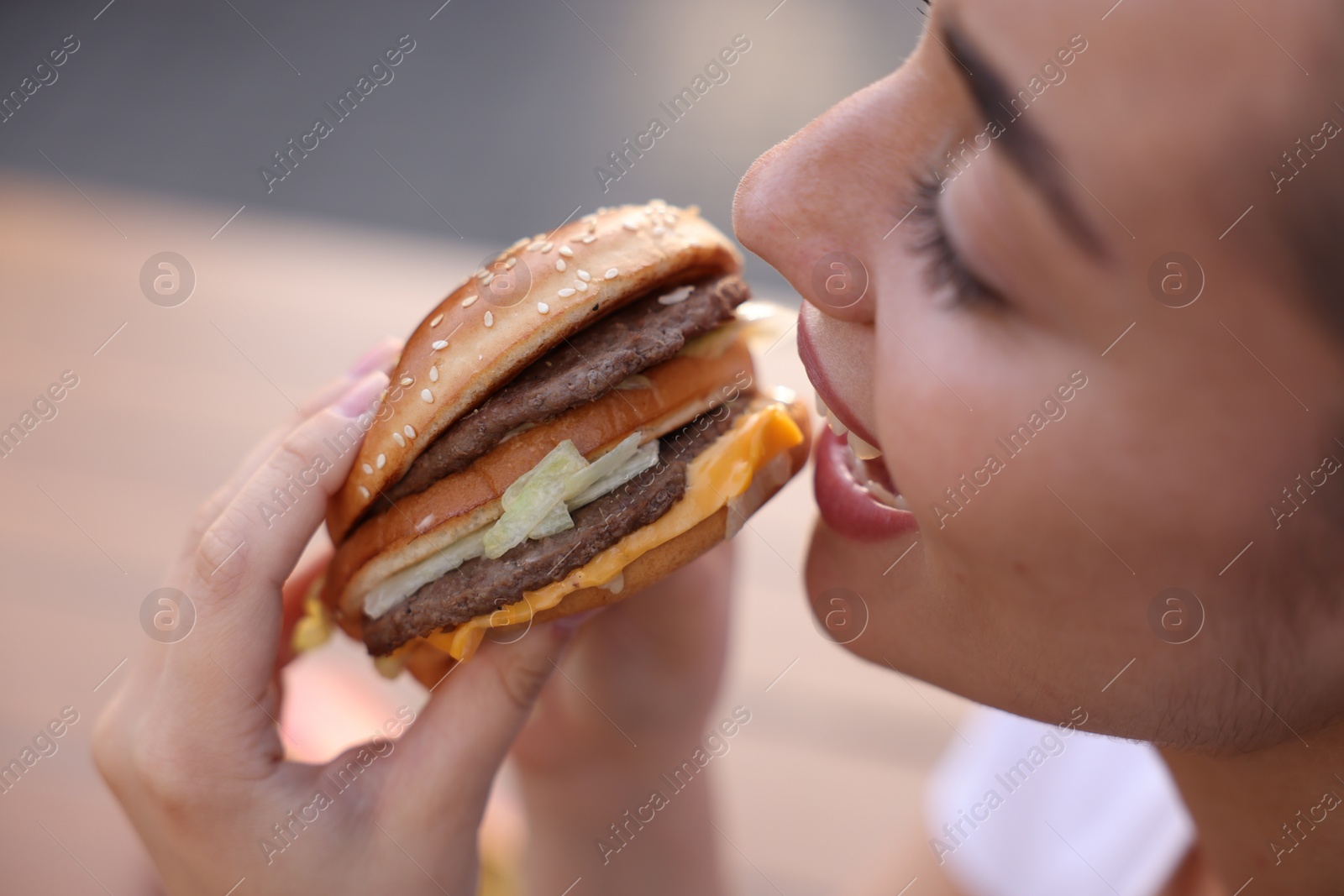 Photo of Lviv, Ukraine - September 26, 2023: Woman eating McDonald's burger outdoors, closeup