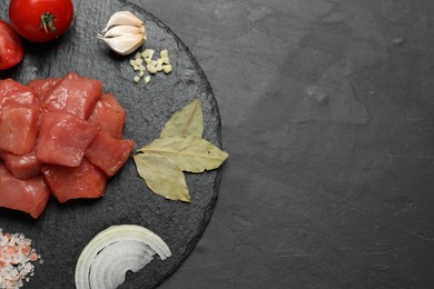 Raw beef meat and different ingredients for cooking delicious goulash on black table, top view. Space for text