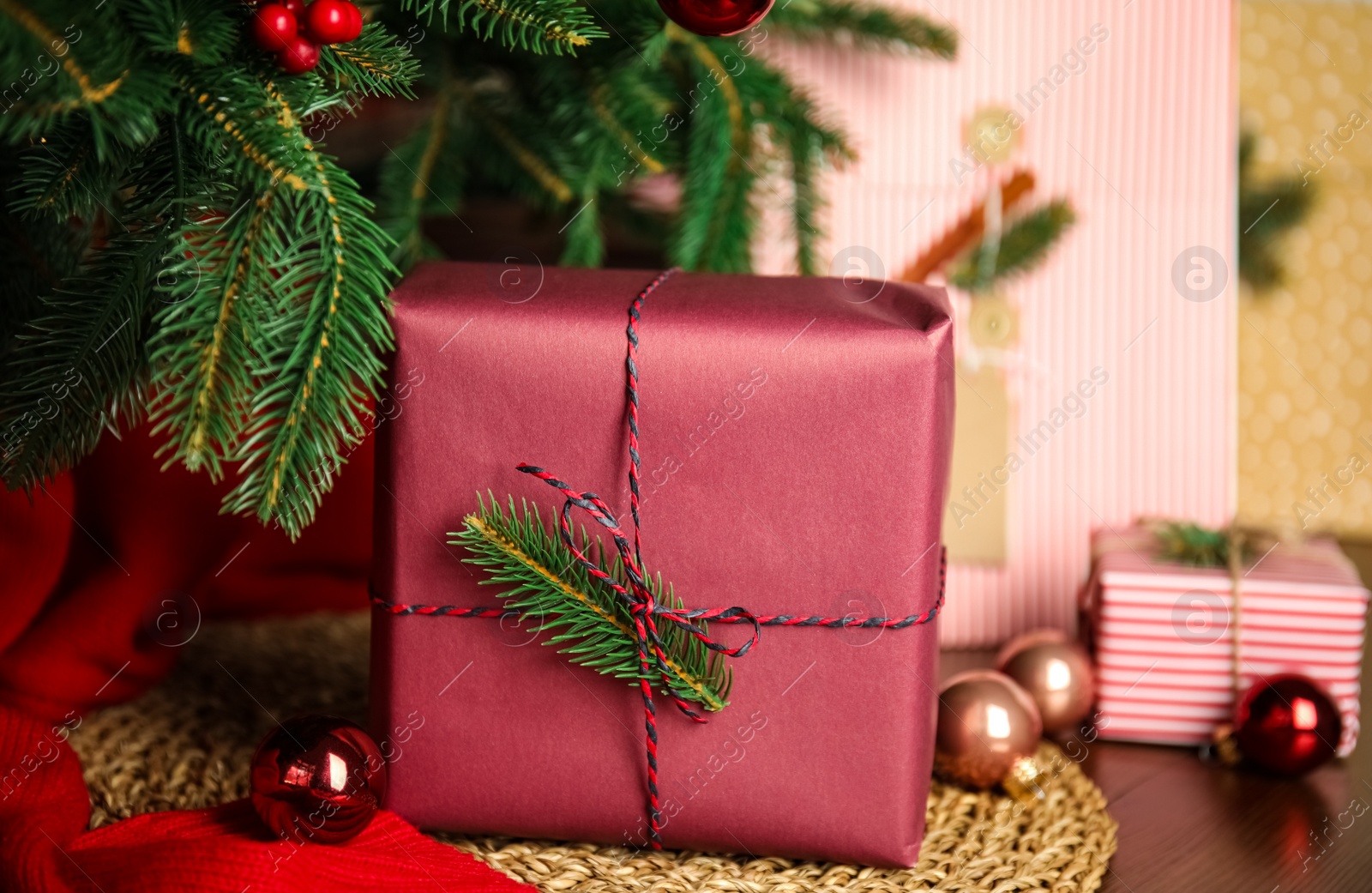 Photo of Beautifully wrapped gift box and Christmas decor on wicker mat