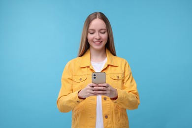 Woman sending message via smartphone on light blue background