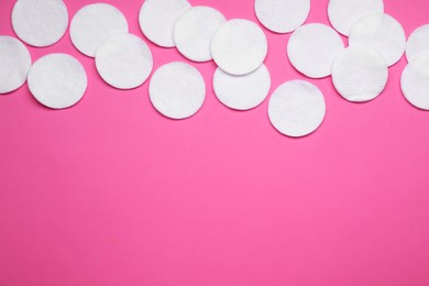 Many cotton pads on pink background, flat lay. Space for text