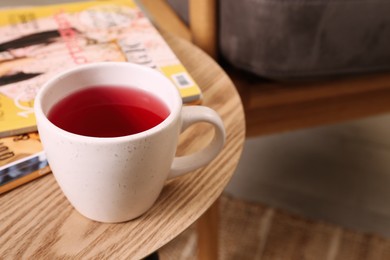 Cup of tea and magazines on wooden table indoors. Space for text