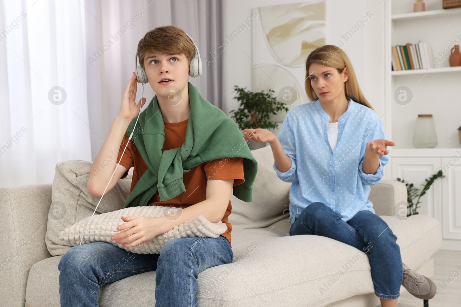 Photo of Teenage son in headphones ignoring his mother at home