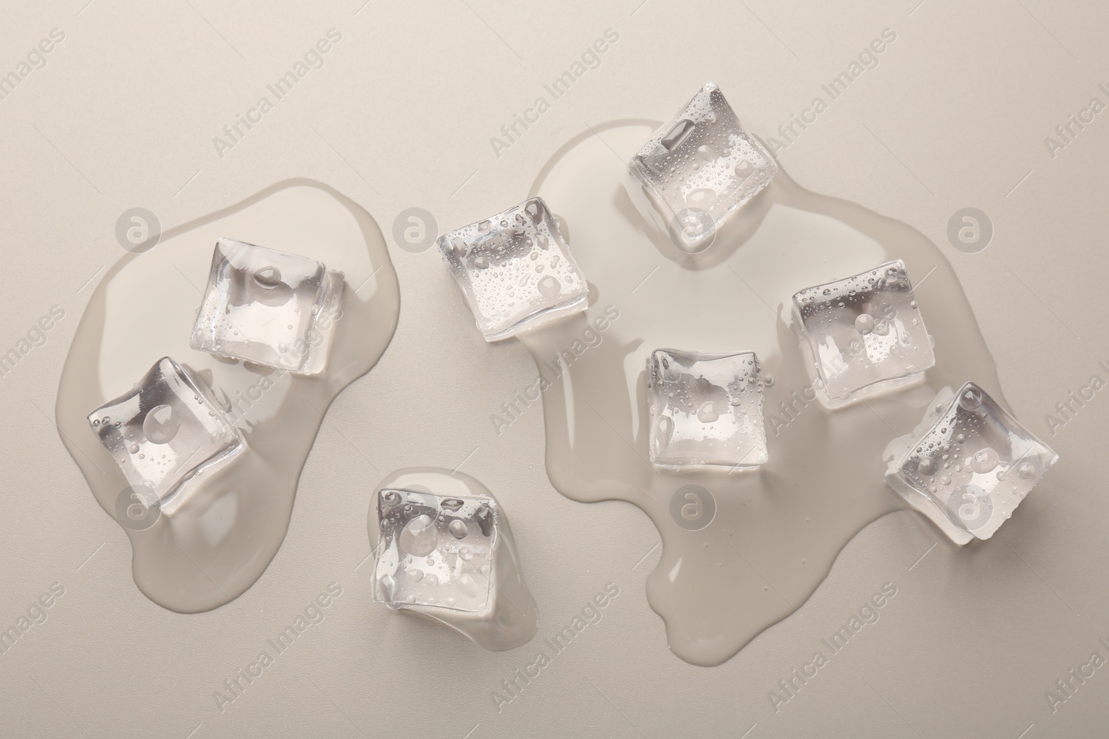 Photo of Melting ice cubes and water drops on light grey background, flat lay