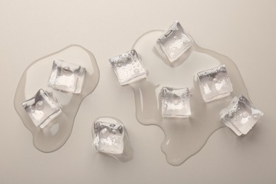 Melting ice cubes and water drops on light grey background, flat lay