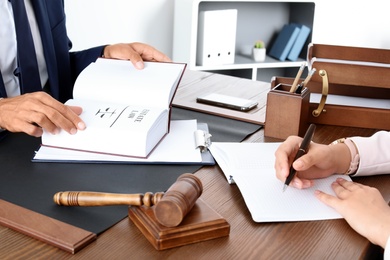 Photo of Male lawyer working with client at table in office