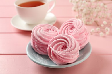 Photo of Delicious zephyrs served with tea on pink wooden table