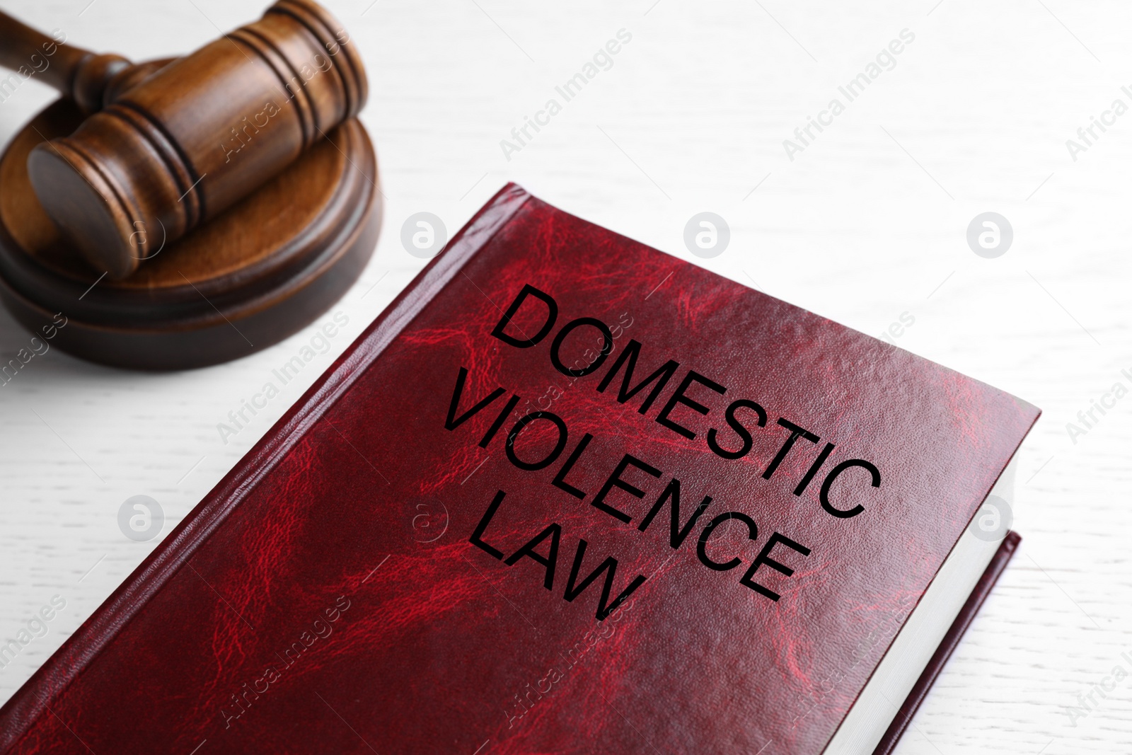Photo of Domestic violence law and gavel on white wooden table, closeup