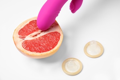 Photo of Half of grapefruit, purple vibrator and condoms on white background. Sex concept