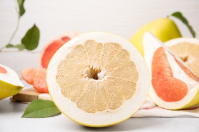 Photo of Different tasty pomelo fruits on white textured table, closeup