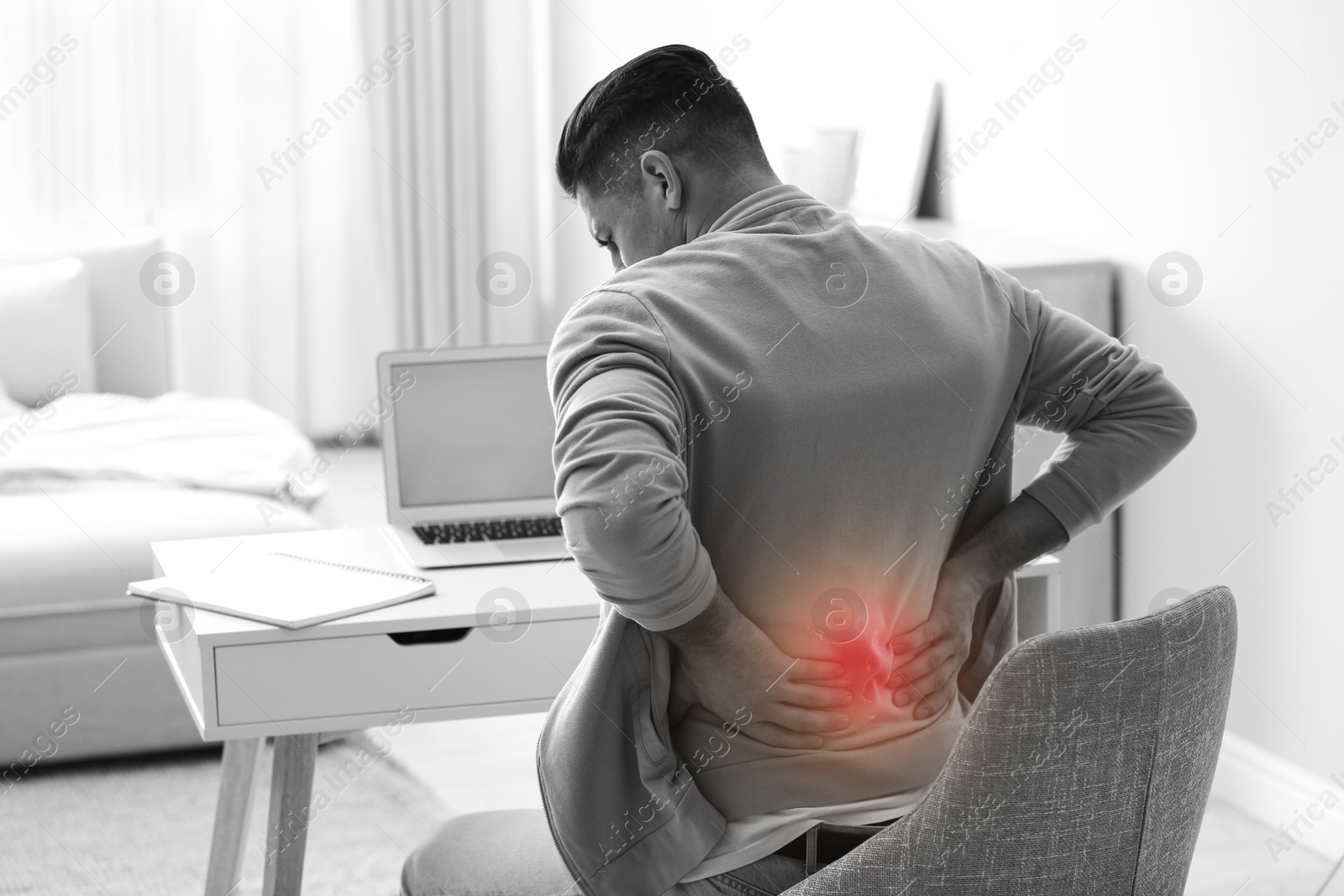 Image of Man suffering from back pain at workplace. Bad posture problem