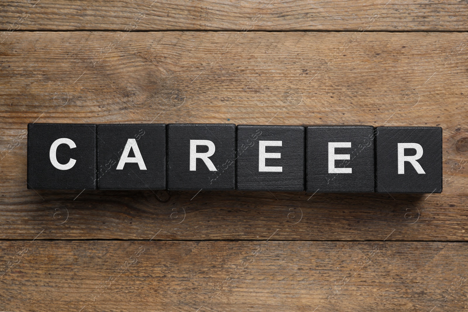 Photo of Black cubes with word CAREER on wooden background, flat lay