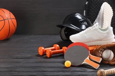 Many different sports equipment on dark grey wooden table